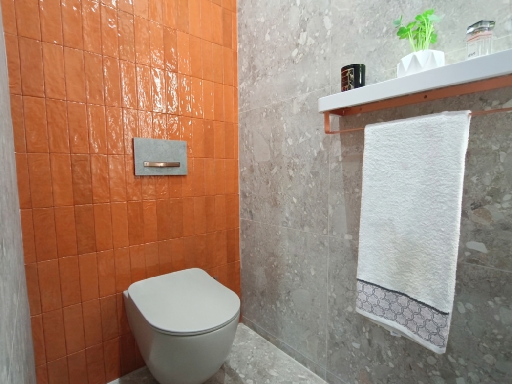 Des carreaux orange contrastent avec des carreaux gris dans une salle de bains du showroom Cerazur.